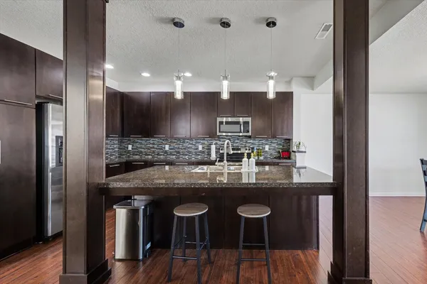 a kitchen with kitchen island granite countertop a sink and refrigerator