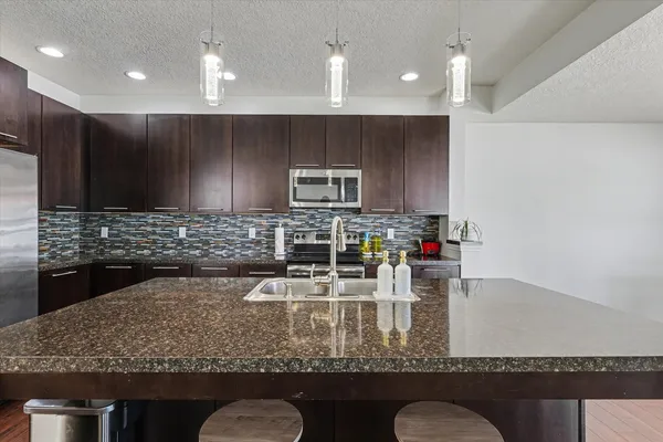 a kitchen with kitchen island granite countertop a refrigerator a stove and a sink