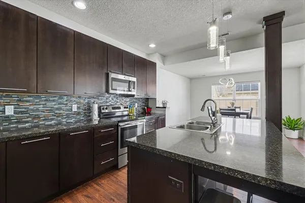 a kitchen with stainless steel appliances granite countertop a sink a stove and a wooden cabinets