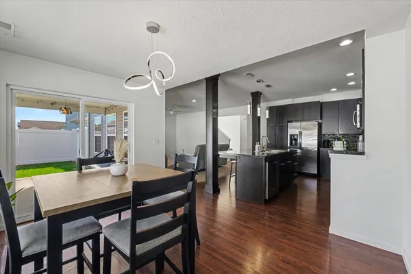 a dining room with furniture a kitchen wooden floor and a rug