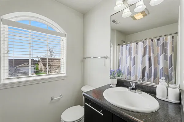 a bathroom with a granite countertop toilet sink and mirror