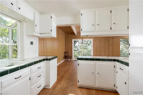 a kitchen with white cabinets and window