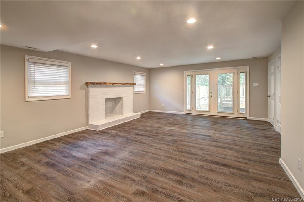 7439 Watercrest Road Charlotte, NC 28210 - Photo 25 of 28 an empty room with wooden floor fireplace and windows