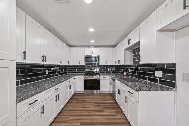 a large kitchen with stainless steel appliances granite countertop a stove and a sink