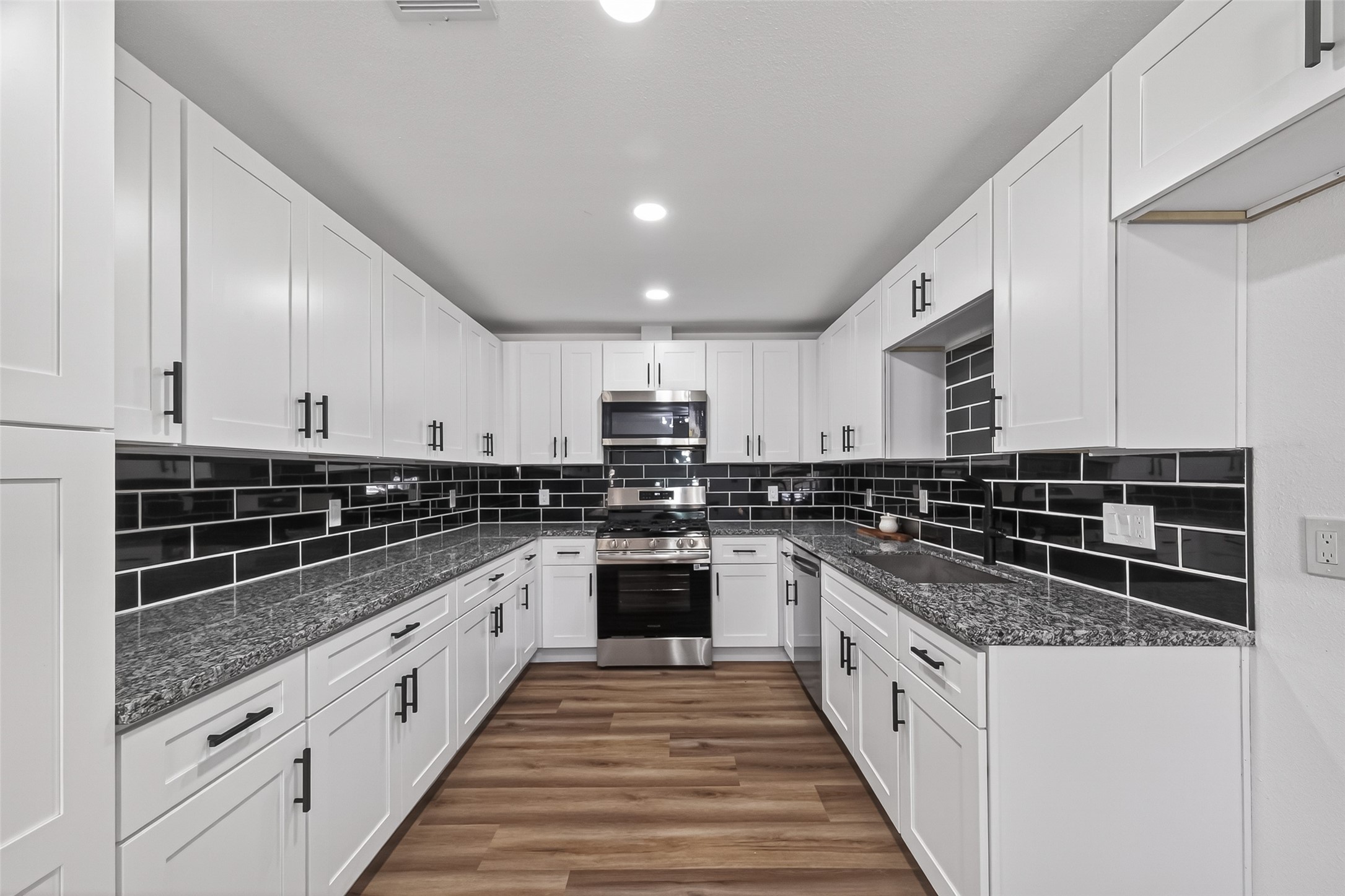 a large kitchen with stainless steel appliances granite countertop a stove and a sink