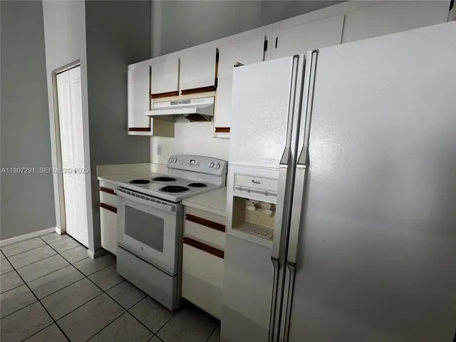 a white refrigerator freezer and a stove sitting inside of a kitchen