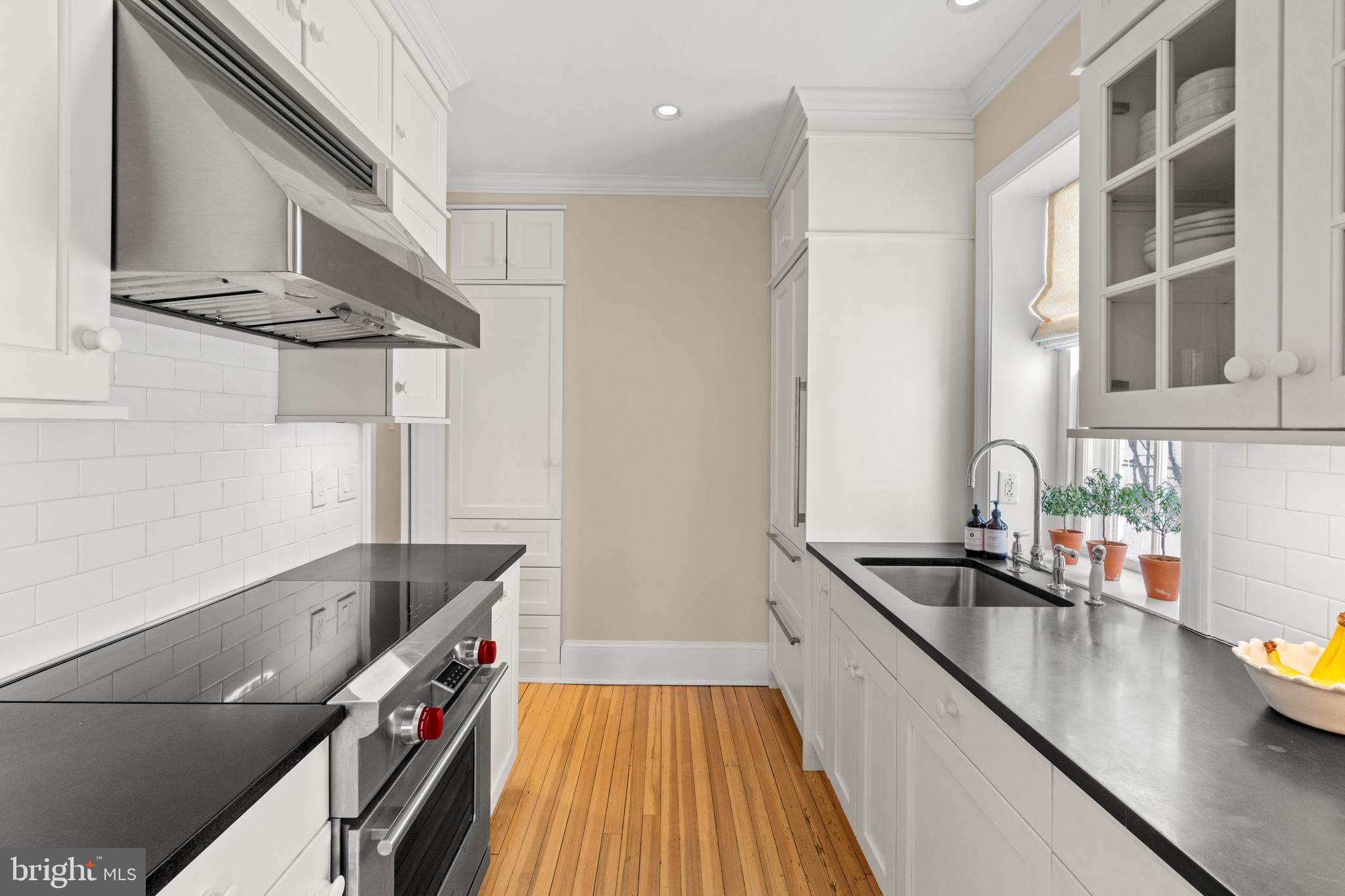 1657 31st Street Northwest, Unit 206 Washington, DC 20007 - Photo 15 of 26 a kitchen with stainless steel appliances a sink a stove and a wooden floor