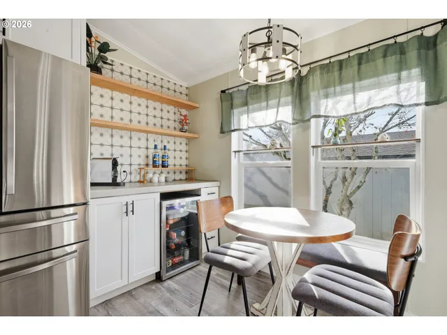 a kitchen with stainless steel appliances kitchen island granite countertop a refrigerator a stove a dining table and chairs with wooden floor