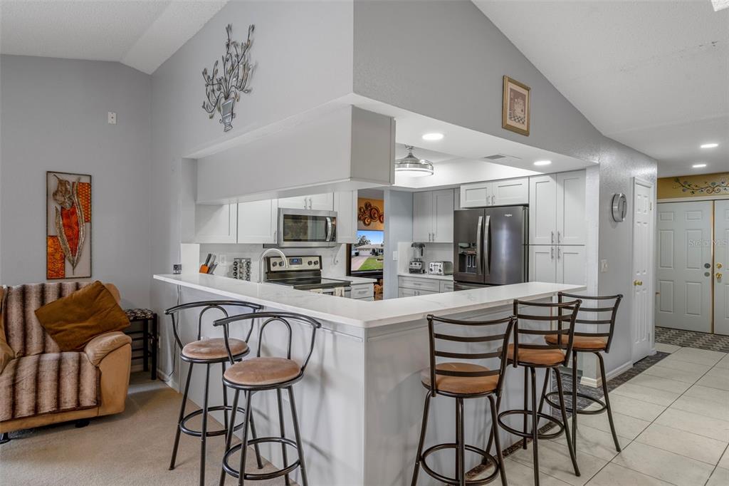 8158 Winding Oak Lane Spring Hill, FL 34606 - Photo 19 of 47 a kitchen with stainless steel appliances kitchen island granite countertop a dining table chairs and a refrigerator
