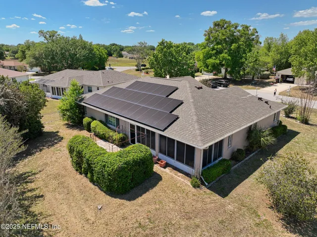 an aerial view of a house with a yard and large tree