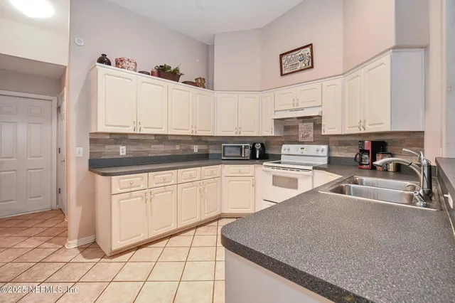 a kitchen with granite countertop white cabinets and white appliances