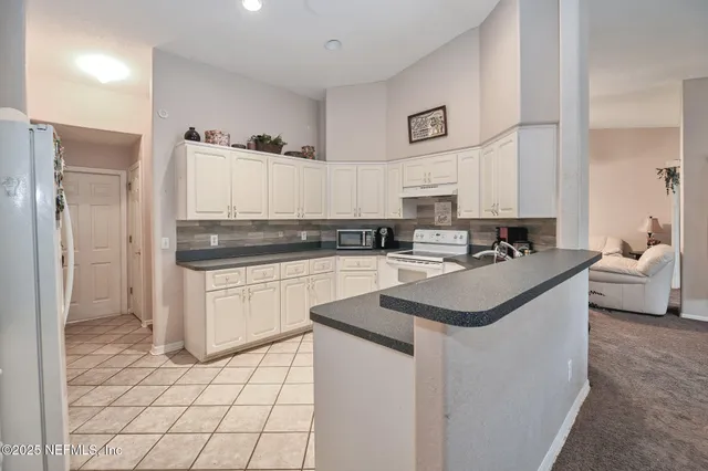 a kitchen with stainless steel appliances a sink a stove a refrigerator and white cabinets