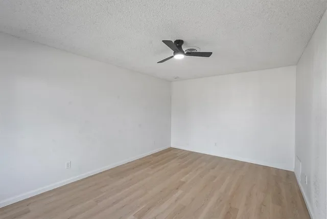 a view of empty room with wooden floor and ceiling fan