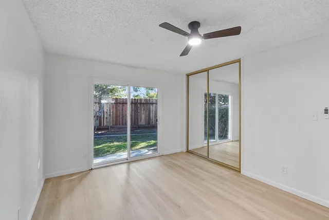 a view of empty room with wooden floor and fan