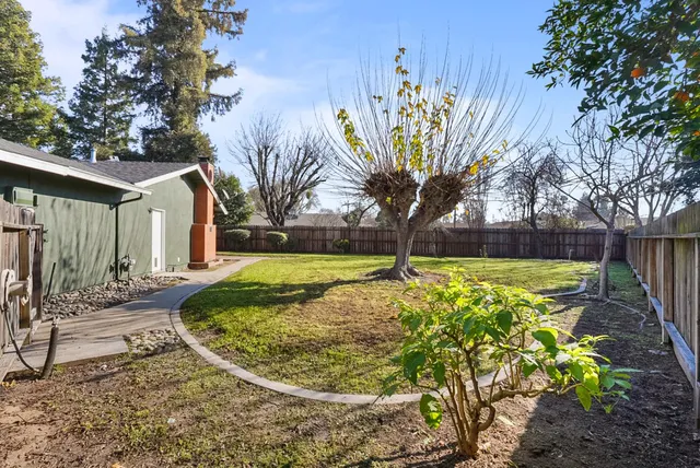 a view of a house with a big yard plants and large trees