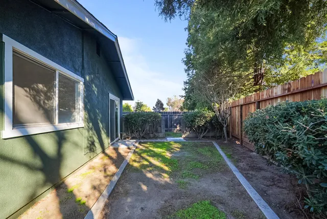 a view of a backyard with wooden fence and large trees