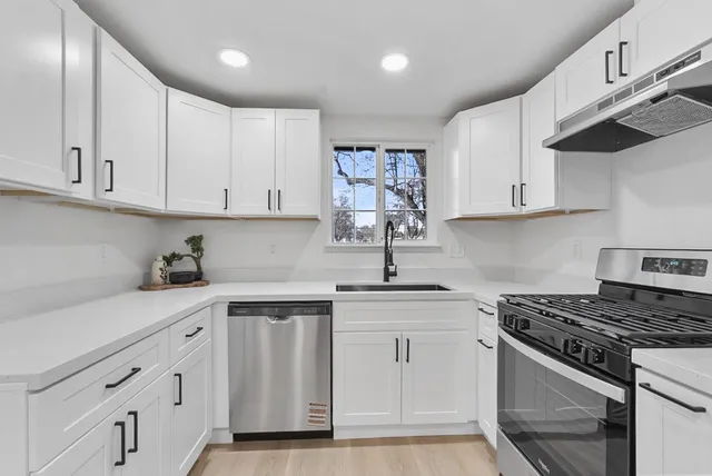 a kitchen with white cabinets and appliances