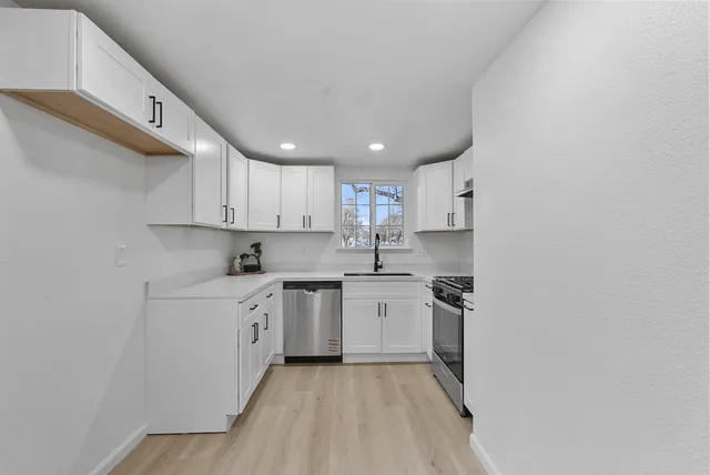 a kitchen with cabinets appliances a sink and a counter top space