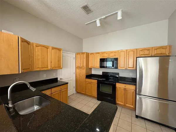a kitchen with stainless steel appliances granite countertop a refrigerator stove top oven and sink