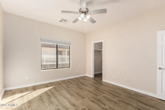 an empty room with chandelier fan and windows