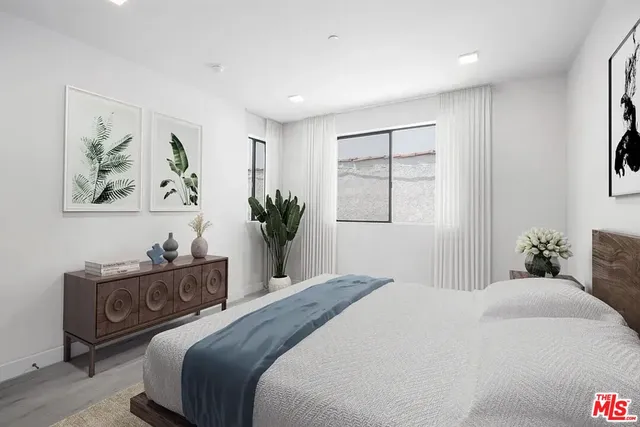 a bedroom with a large bed and a potted plant