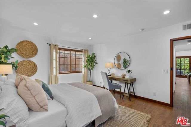 a bedroom with a bed a window and potted plant on a dresser