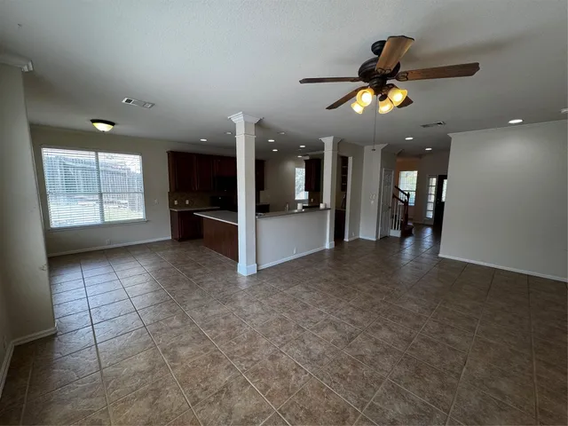 an empty room with chandelier fan and windows