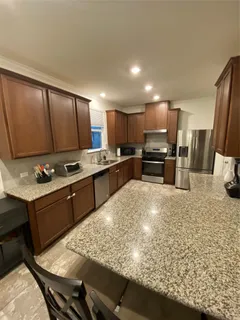 a kitchen with stainless steel appliances kitchen island granite countertop a sink stove and refrigerator