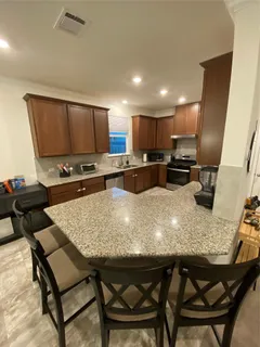 a kitchen with kitchen island granite countertop a table chairs sink and microwave