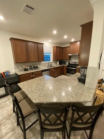 a kitchen with kitchen island granite countertop a table chairs sink and microwave