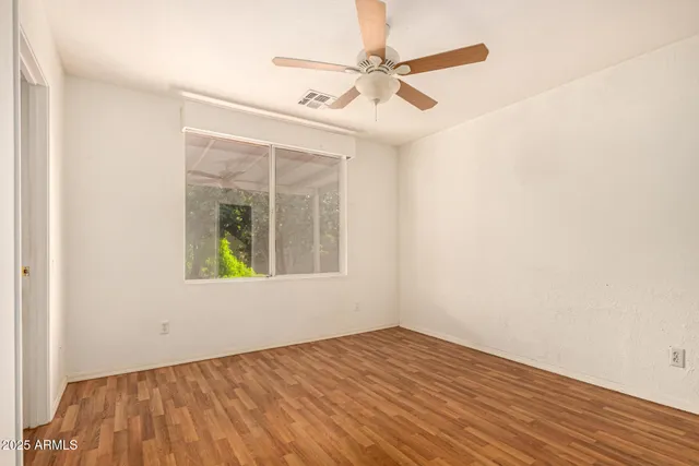 an empty room with wooden floor and a ceiling fan