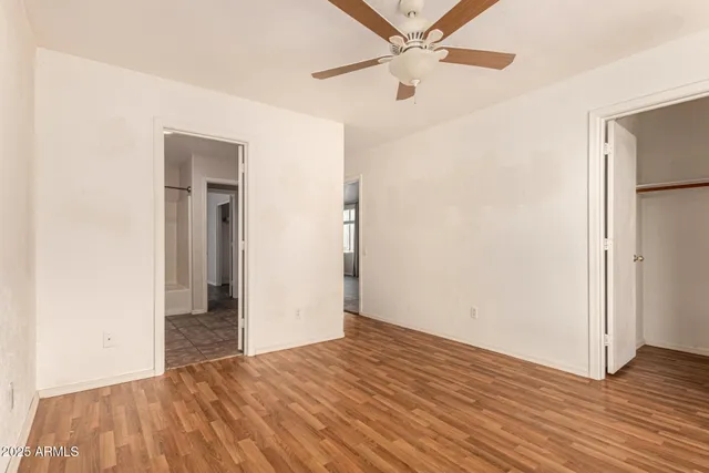 an empty room with wooden floor fan and windows
