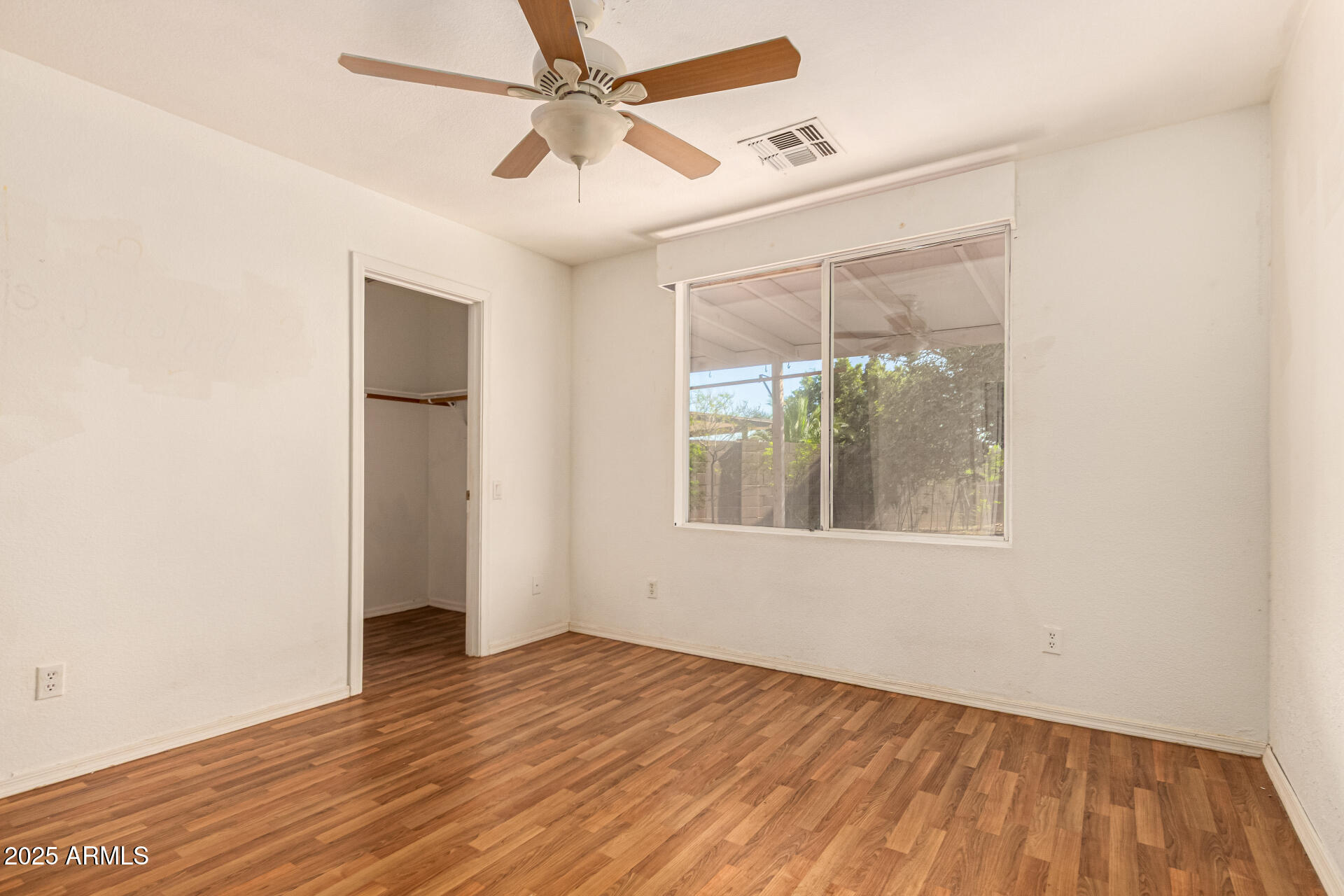 2279 West 20th Avenue Apache Junction, AZ 85120 - Photo 17 of 28 an empty room with wooden floor fan and windows