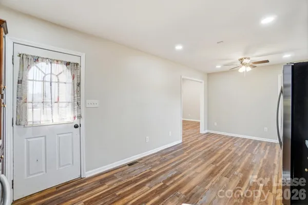 a view of an empty room with wooden floor and a window