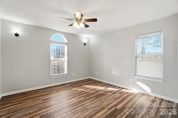 an empty room with wooden floor and ceiling fan