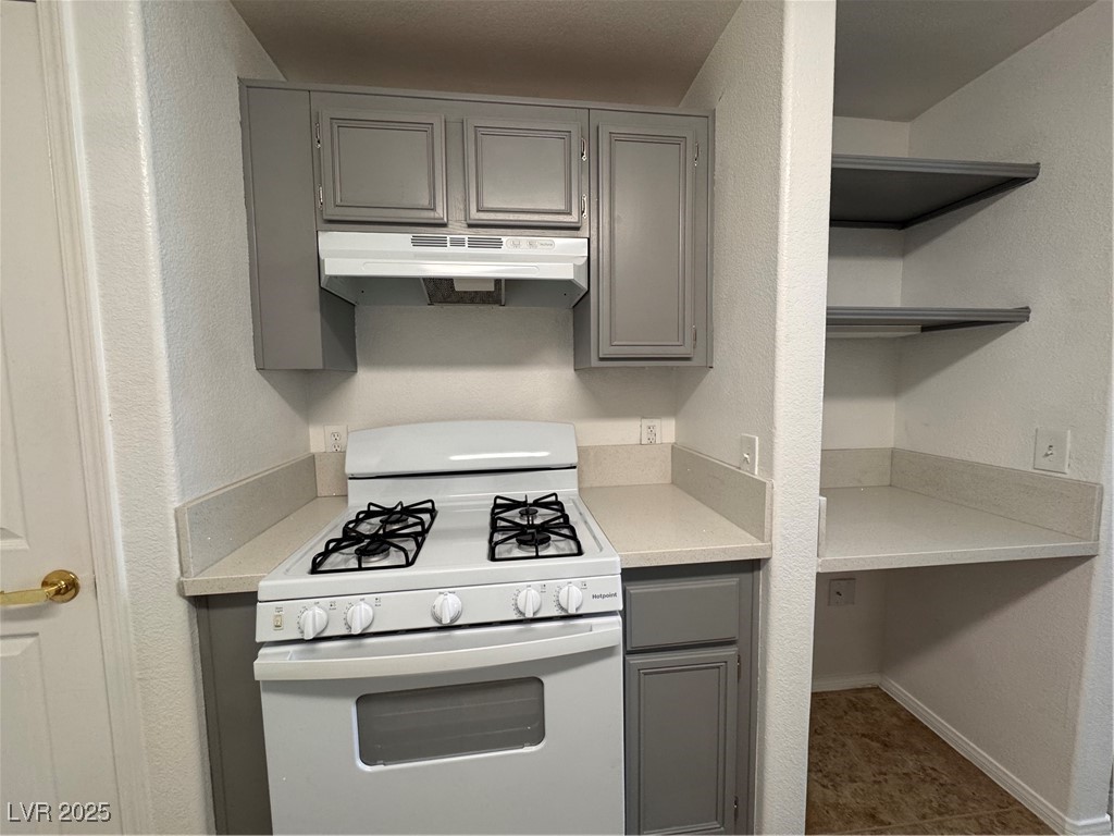 9975 Peace Way, Unit 1140 Las Vegas, NV 89147 - Photo 5 of 23 Kitchen with range, open shelves, ventilation hood, and gray cabinets