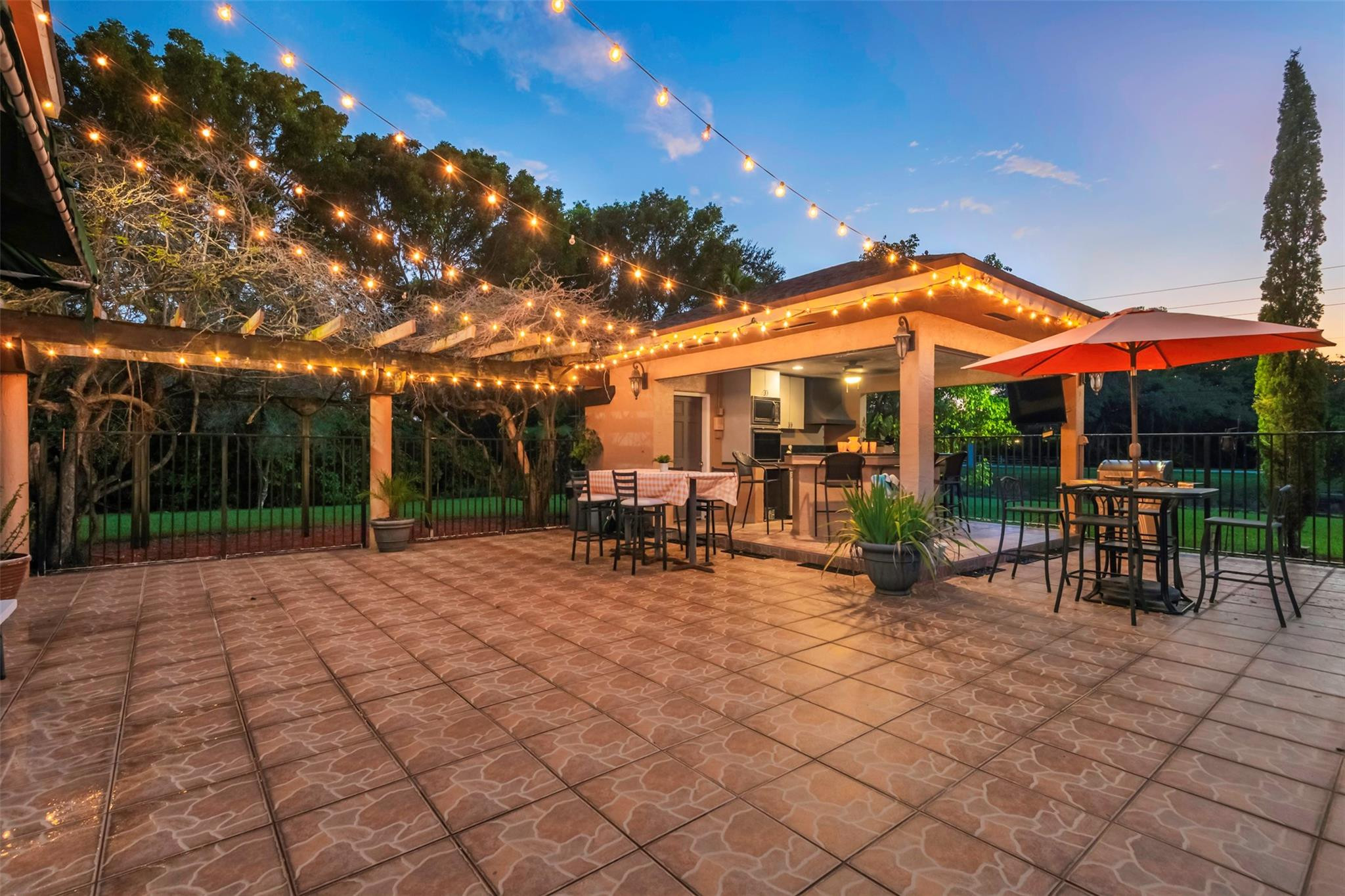 3151 Southwest 135th Terrace Davie, FL 33330 - Photo 68 of 74 a view of a patio with dining table and chairs under an umbrella with a fire pit