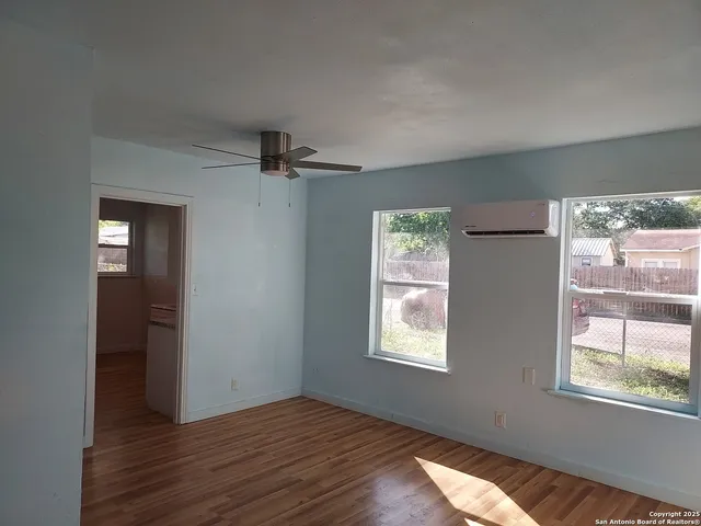 a view of an empty room with wooden floor and a window