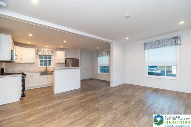 a view of kitchen with kitchen island wooden floors and stainless steel appliances
