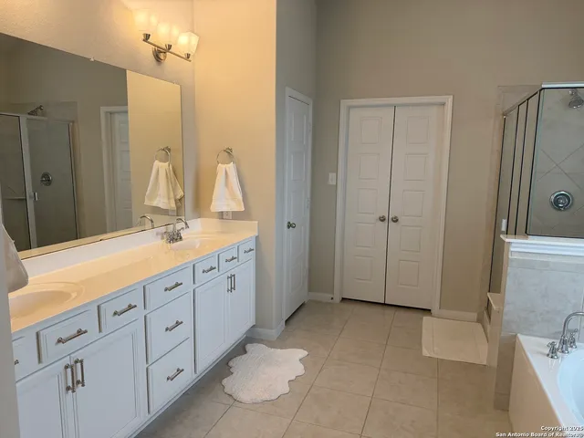 a spacious bathroom with a double vanity sink a mirror and a shower