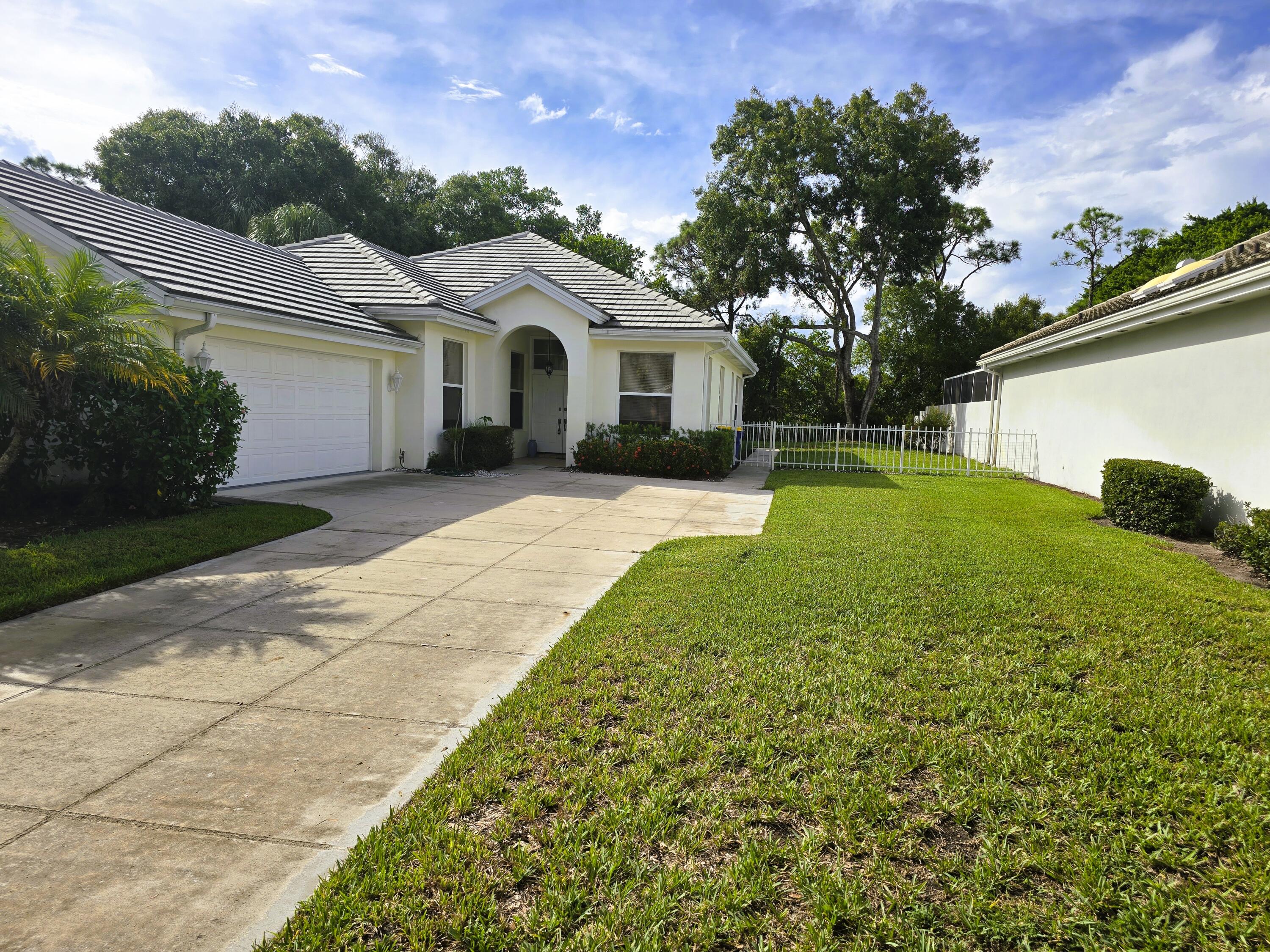 5131 Southeast Sweetbrier Terrace Hobe Sound, FL 33455 - Photo 17 of 18 a view of a white house with a yard and plants