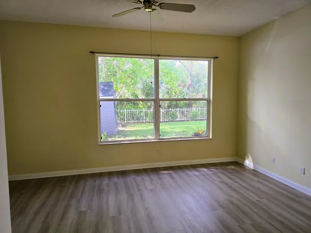 a view of an empty room with a window and wooden floor