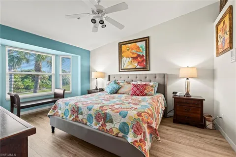 a bedroom with a bed two lamps and a large window