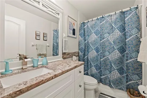 a bathroom with a granite countertop sink mirror vanity and toilet