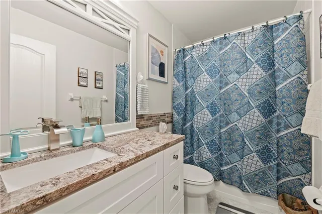 a bathroom with a granite countertop sink mirror vanity and toilet