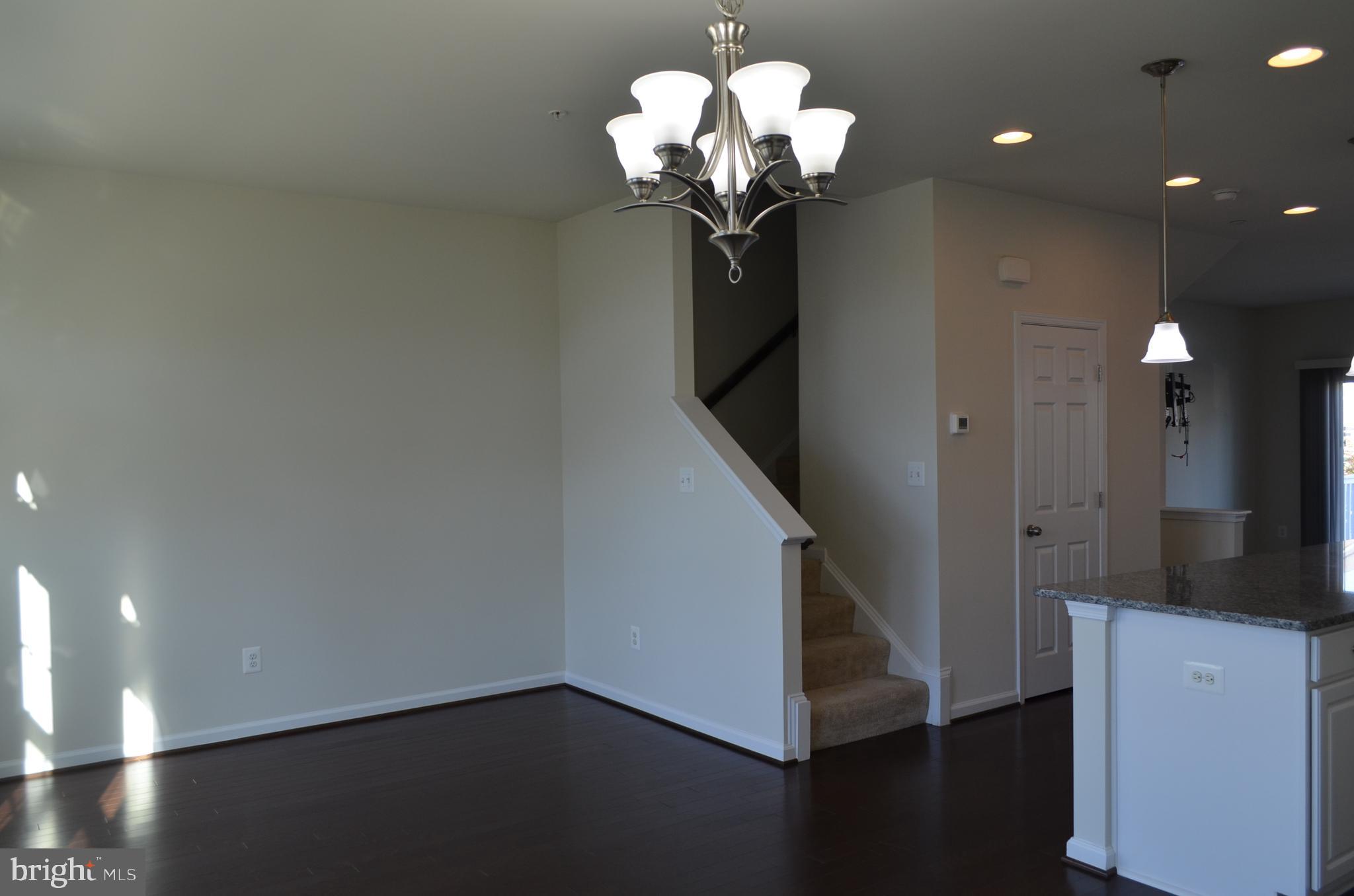 6004 Forum Frederick, MD 21703 - Photo 10 of 30 a dining room with wooden floor a chandelier a glass door and a chandelier