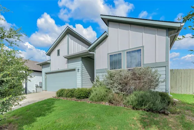 a view of a house with brick walls and a yard with plants