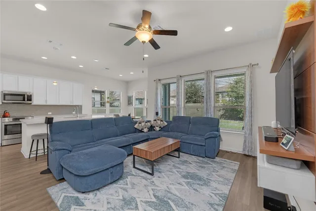 a living room with couches a coffee table and a flat screen tv with kitchen view