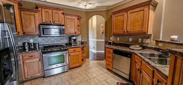 a kitchen with stainless steel appliances granite countertop a stove a sink and a microwave