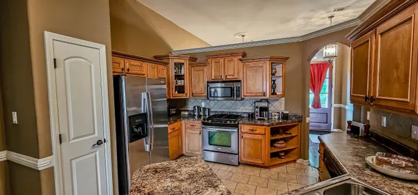 a kitchen with stainless steel appliances granite countertop a stove top oven a sink and a refrigerator